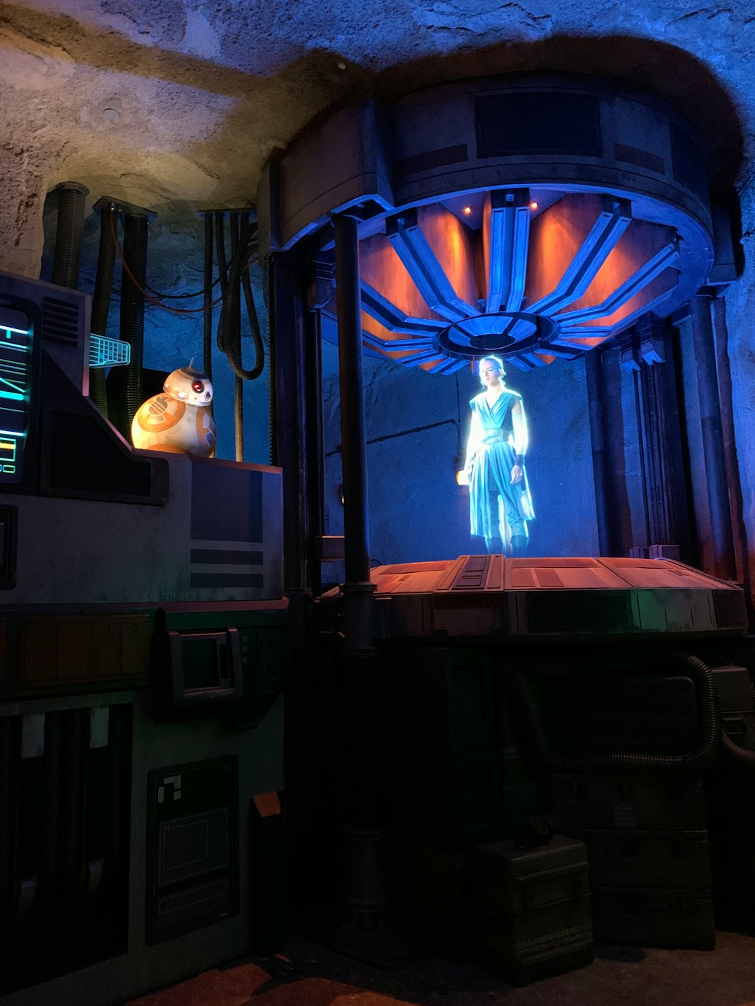 Woman's holographic projection with droid in futuristic chamber.