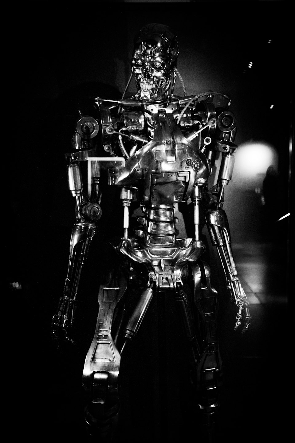 Metallic robot endoskeleton standing in a dark industrial setting.